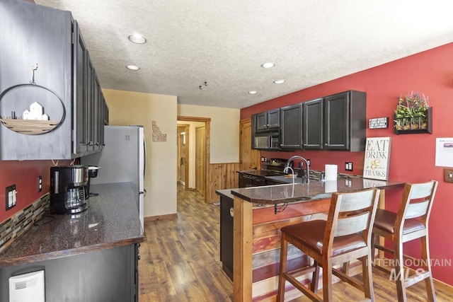 13098 Hillhouse Loop, Donnelly, ID 83615 - kitchen with black appliances, a peninsula, dark wood-type flooring, a breakfast bar area, and recessed lighting