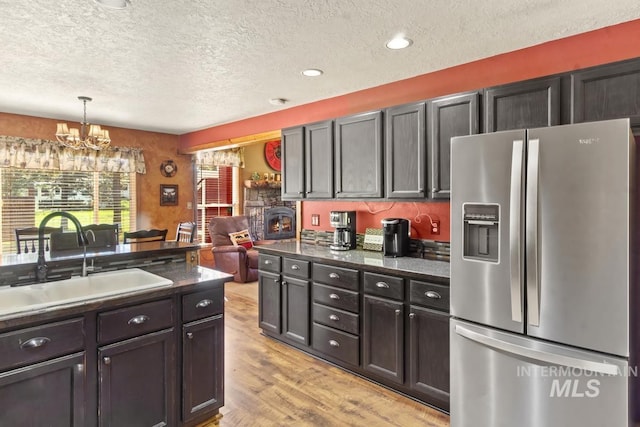 13098 Hillhouse Loop, Donnelly, ID 83615 - kitchen featuring stainless steel refrigerator with ice dispenser, a sink, a textured ceiling, dark countertops, and a chandelier