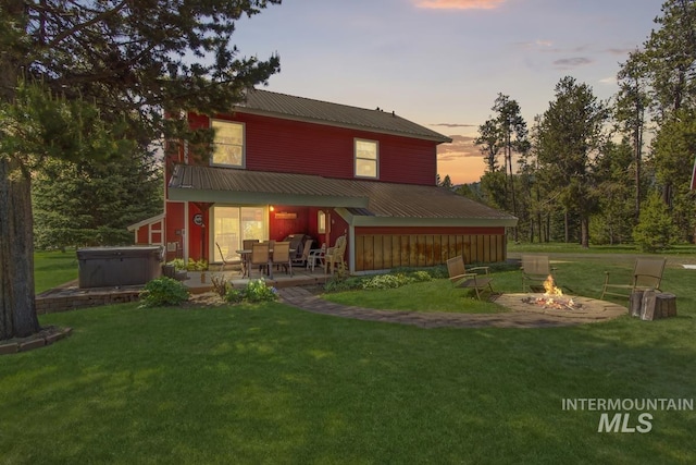13098 Hillhouse Loop, Donnelly, ID 83615 - rear view of house with a hot tub, an outdoor fire pit, metal roof, a lawn, and a patio