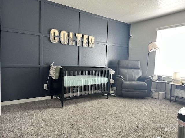 bedroom with a textured ceiling, carpet flooring, and a crib