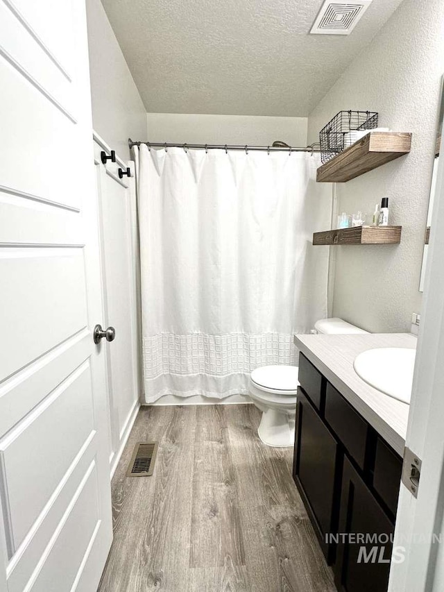 bathroom featuring vanity, toilet, hardwood / wood-style flooring, and a textured ceiling