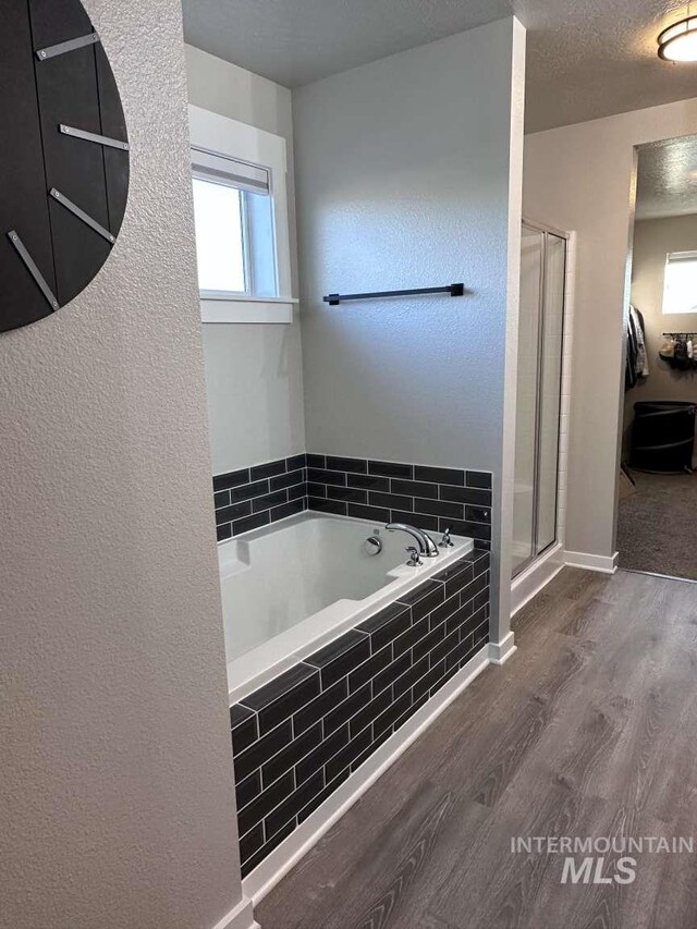 bathroom featuring a textured ceiling, hardwood / wood-style flooring, and separate shower and tub