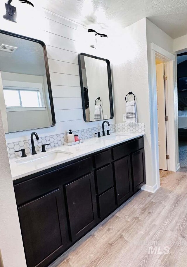 bathroom with vanity, hardwood / wood-style floors, a textured ceiling, and tasteful backsplash