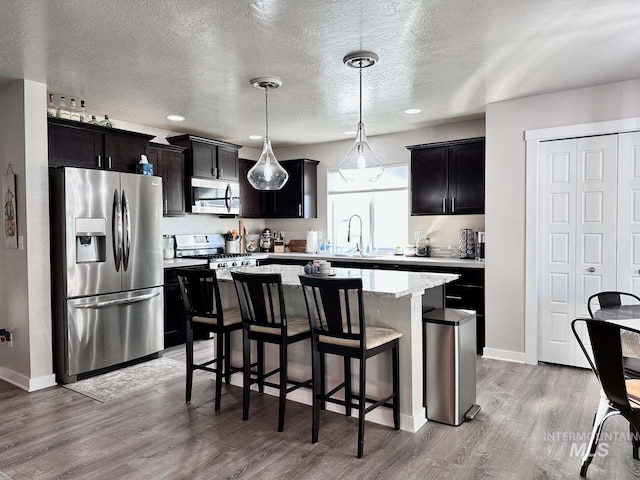 kitchen with light hardwood / wood-style floors, appliances with stainless steel finishes, a textured ceiling, and a kitchen island