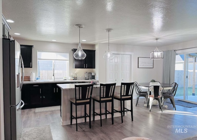 kitchen featuring a textured ceiling, stainless steel fridge, a wealth of natural light, and a kitchen island