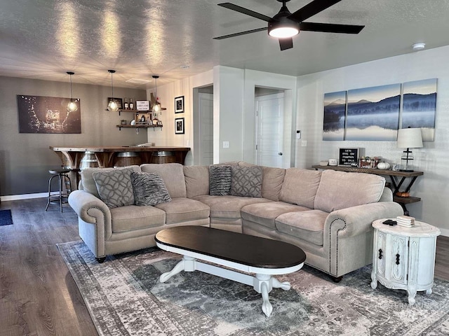 living room featuring ceiling fan, a textured ceiling, and dark hardwood / wood-style flooring