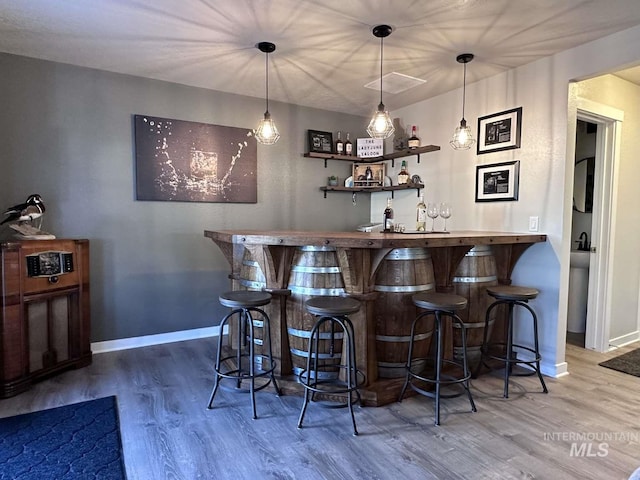 bar featuring hardwood / wood-style flooring and hanging light fixtures