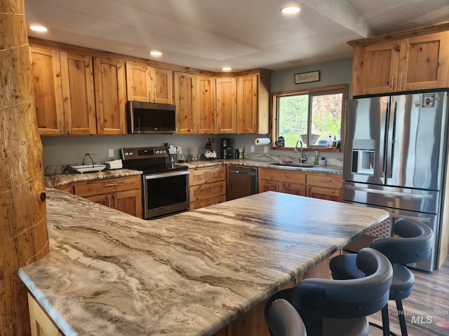 131 Beaver Nob Dr, Kamiah, ID 83536 - kitchen with stainless steel appliances, a sink, a breakfast bar, light stone counters, and recessed lighting