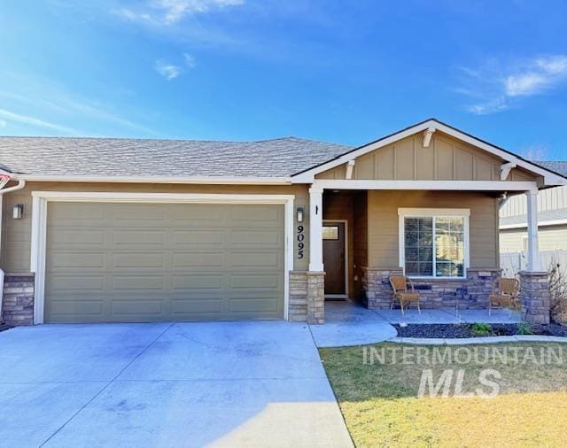 view of front of house with driveway, stone siding, a garage, and board and batten siding