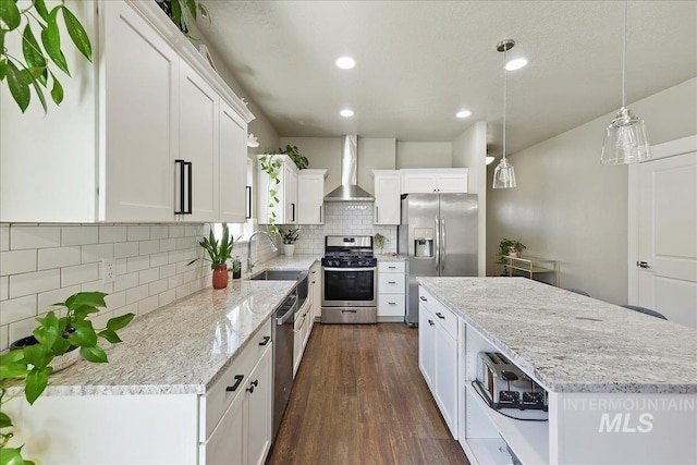 kitchen with stainless steel appliances, a sink, white cabinetry, a center island, and wall chimney exhaust hood