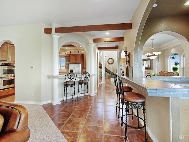 16480 Goodson Rd, Caldwell, ID 83607 - kitchen with tile flooring, appliances with stainless steel finishes, a breakfast bar, a notable chandelier, and plenty of natural light