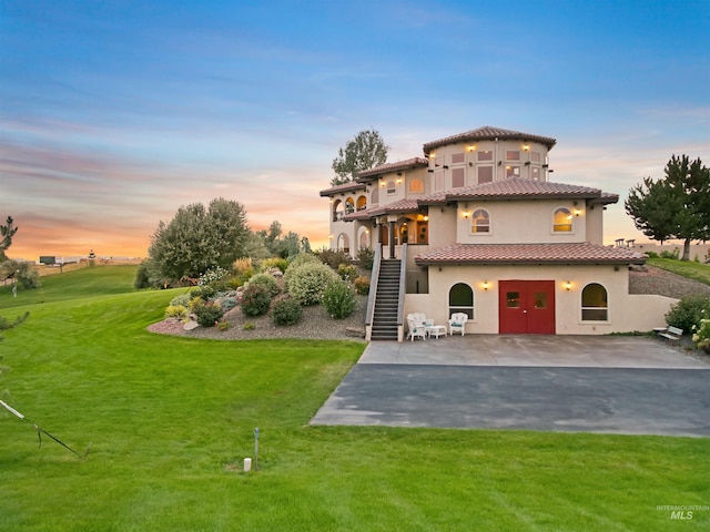 16480 Goodson Rd, Caldwell, ID 83607 - back house at dusk featuring a patio area and a lawn