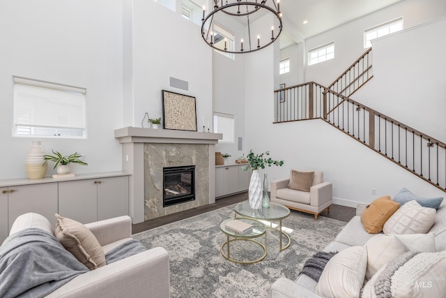 living room with hardwood / wood-style floors, a high ceiling, a fireplace, and an inviting chandelier