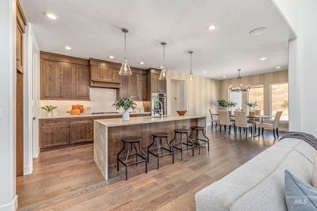 kitchen featuring pendant lighting, a breakfast bar, dark hardwood / wood-style floors, stainless steel gas stovetop, and a spacious island