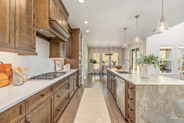 kitchen featuring appliances with stainless steel finishes, hanging light fixtures, a spacious island, hardwood / wood-style floors, and sink