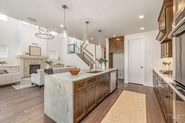 kitchen featuring an island with sink, sink, decorative light fixtures, dark hardwood / wood-style floors, and a fireplace