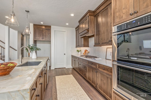 kitchen with dark wood-type flooring, backsplash, light stone countertops, stainless steel appliances, and sink