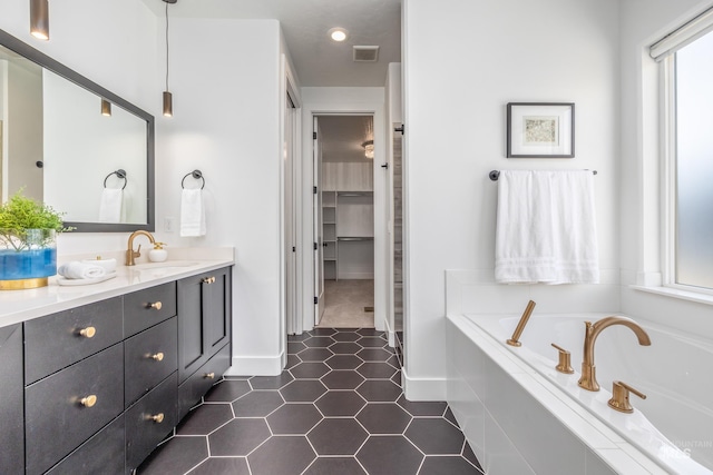 bathroom featuring tile patterned floors, tiled bath, and vanity