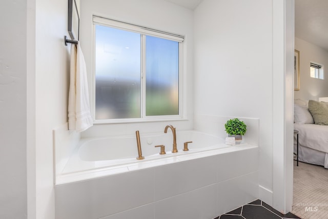 bathroom featuring tiled bath and a wealth of natural light