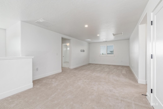 empty room featuring light carpet and a textured ceiling