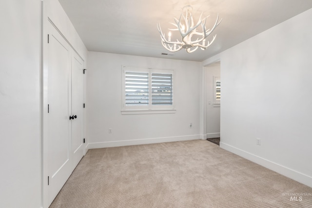 empty room with an inviting chandelier and light colored carpet