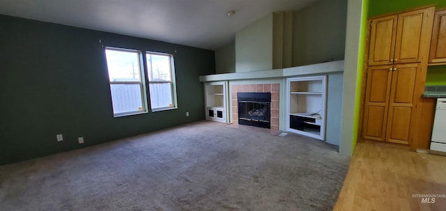 unfurnished living room featuring light carpet, a tile fireplace, and vaulted ceiling