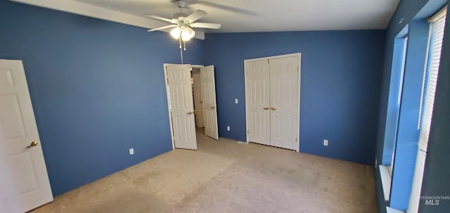 unfurnished bedroom featuring lofted ceiling, a closet, carpet floors, and ceiling fan