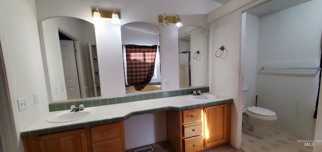 bathroom featuring double vanity, toilet, and a sink