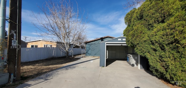 view of patio featuring an outbuilding, driveway, fence, a storage shed, and a garage