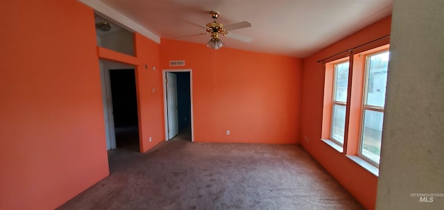 carpeted empty room with visible vents, lofted ceiling, and ceiling fan