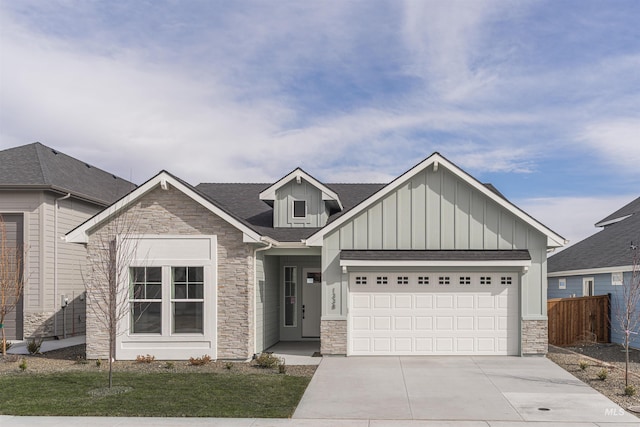 view of front of property with a garage, fence, concrete driveway, stone siding, and board and batten siding