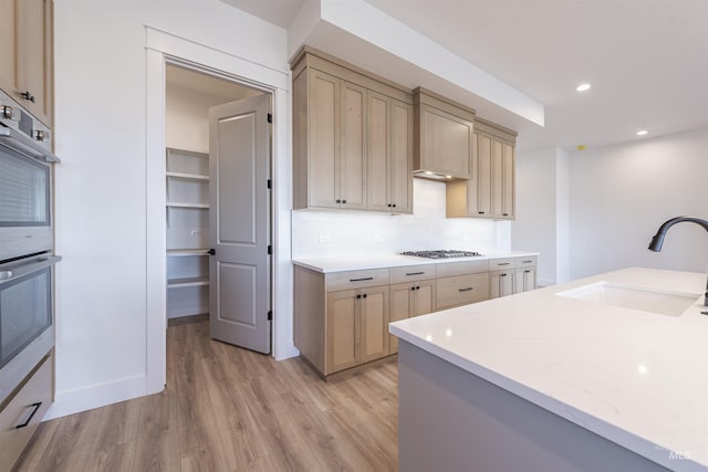 kitchen with recessed lighting, stainless steel appliances, a sink, decorative backsplash, and light wood finished floors