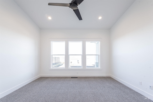 carpeted empty room featuring lofted ceiling, visible vents, baseboards, and ceiling fan