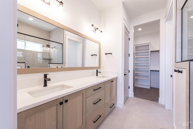 bathroom featuring a walk in closet, a sink, a shower stall, and double vanity