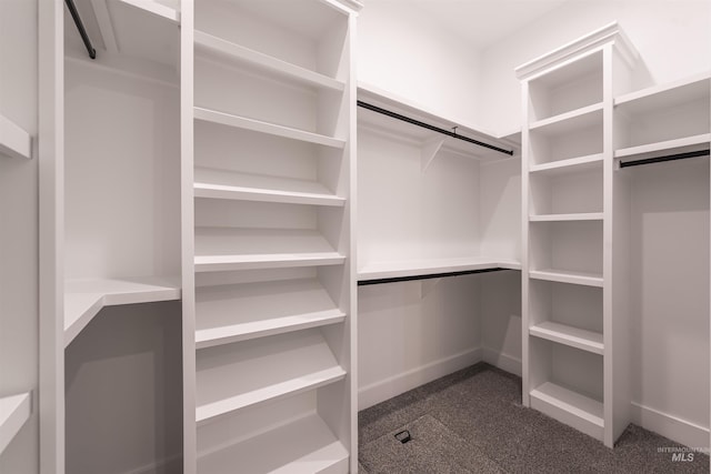 walk in closet featuring dark colored carpet