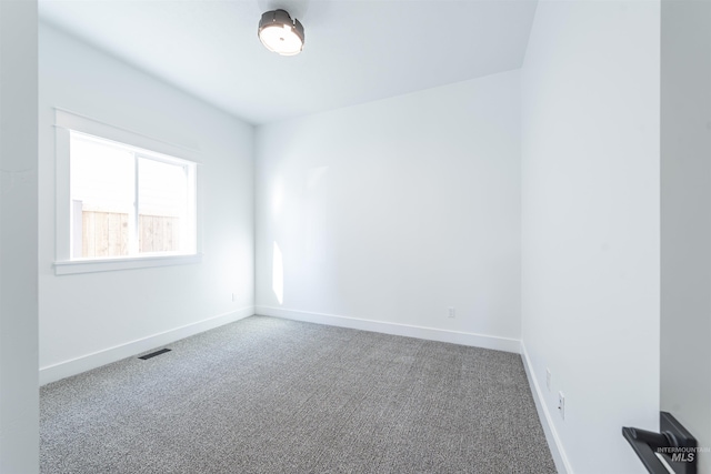 unfurnished room with carpet floors, visible vents, and baseboards