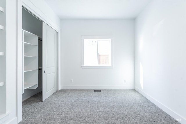 unfurnished bedroom with carpet floors, a closet, visible vents, and baseboards