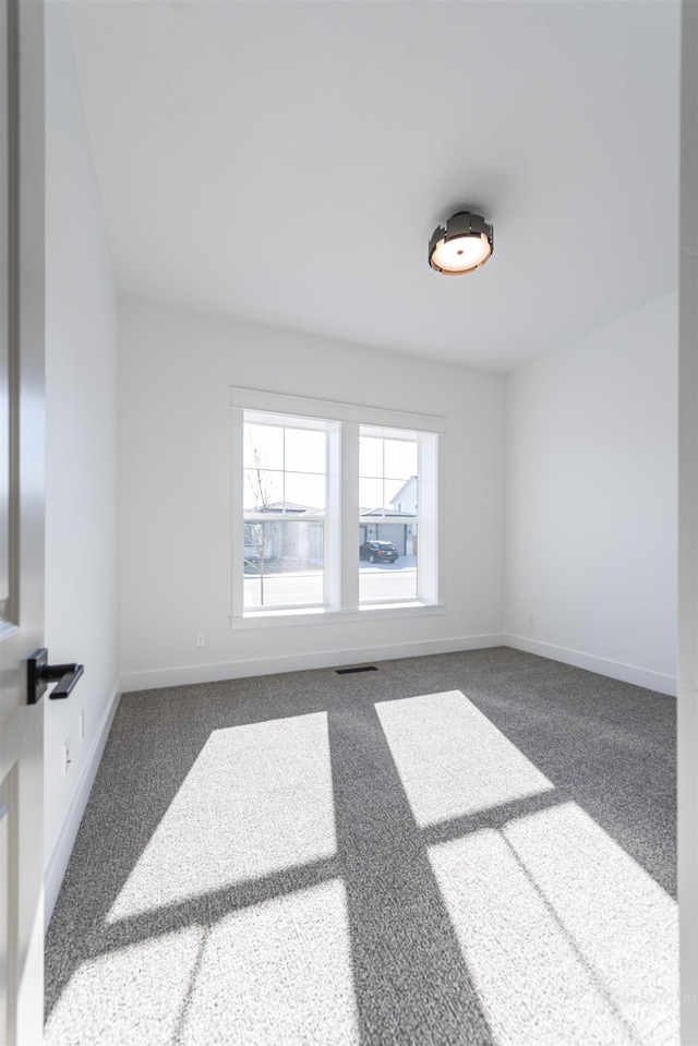 spare room with carpet floors, visible vents, and baseboards