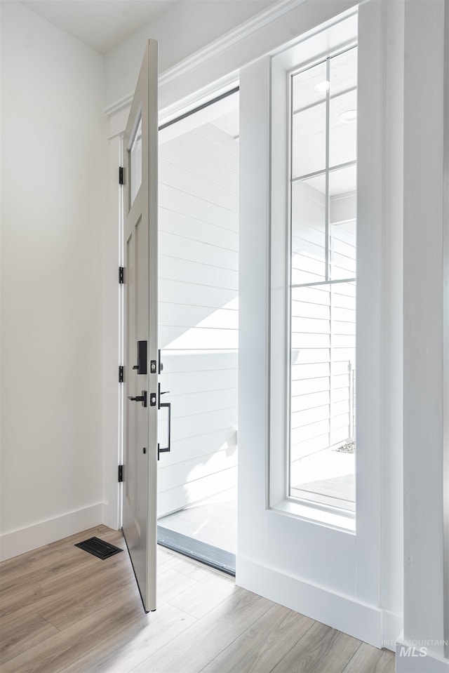 doorway with visible vents, light wood-style flooring, and baseboards