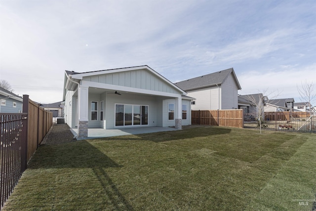 rear view of property with a yard, board and batten siding, a patio area, ceiling fan, and a fenced backyard