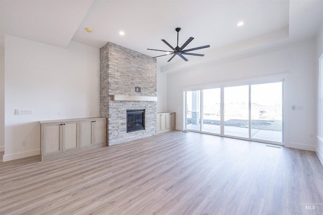 unfurnished living room with light wood finished floors, baseboards, ceiling fan, a stone fireplace, and recessed lighting