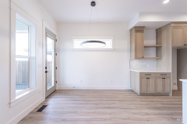 kitchen featuring light wood finished floors, tasteful backsplash, visible vents, and baseboards