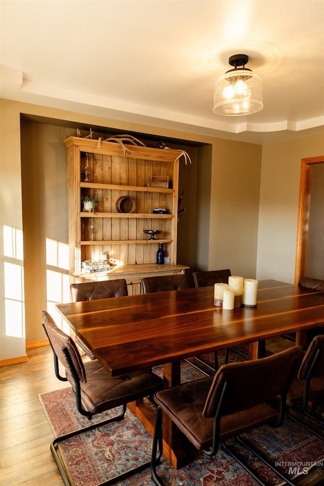 dining area featuring light wood-type flooring and a tray ceiling