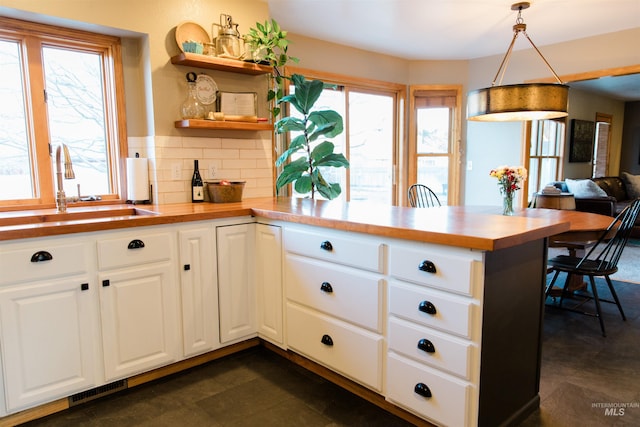 kitchen featuring kitchen peninsula, a wealth of natural light, hanging light fixtures, and sink