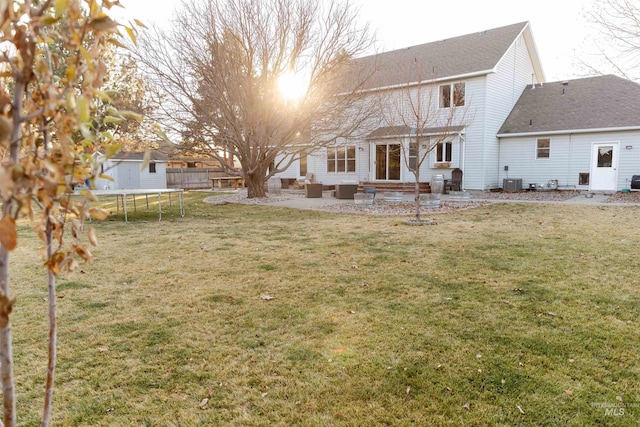 rear view of property with a patio, central air condition unit, an outdoor living space, a yard, and a trampoline