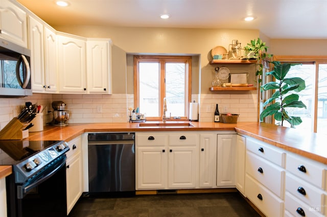 kitchen featuring butcher block counters, white cabinetry, sink, stainless steel appliances, and tasteful backsplash