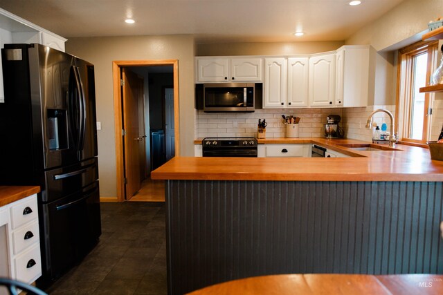 kitchen with sink, stainless steel appliances, wood counters, kitchen peninsula, and white cabinets