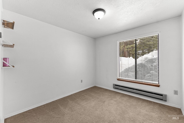 spare room with a baseboard heating unit, baseboards, carpet floors, and a textured ceiling