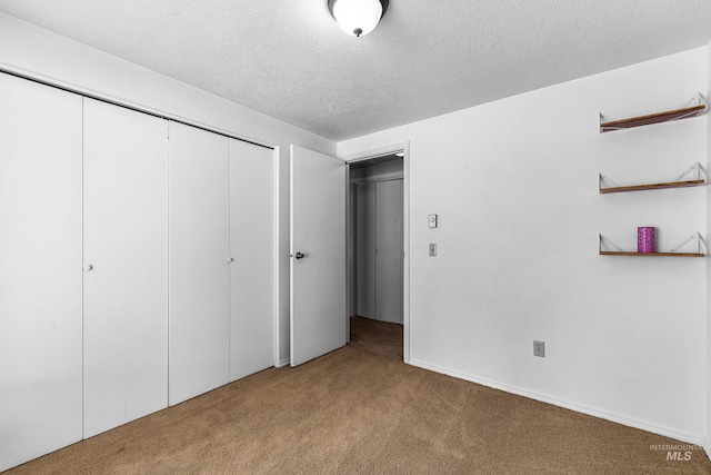 unfurnished bedroom featuring a textured ceiling, a closet, and carpet flooring