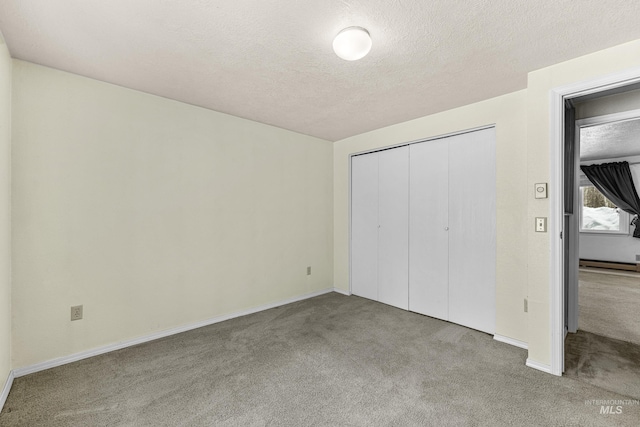 unfurnished bedroom featuring carpet floors, a baseboard radiator, a closet, and a textured ceiling